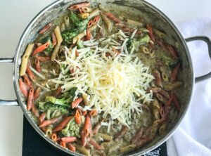 cheese added to a pot with penne noodles, chicken breast, broccoli and roux