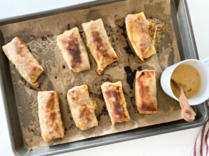 Philly cheesesteak egg rolls browned in the oven with honey mustard sauce