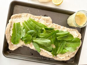 Add on the romaine lettuce to the grilled Caesar salad pizza.