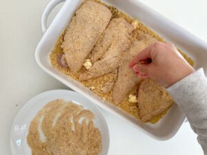 Add the chicken to the casserole pan, add more breadcrumbs.