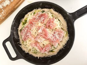 Add on the prosciutto slices and grated Parmesan cheese. Sprinkle a little cheese on the crust too!