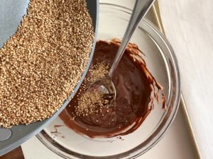 Pouring popped quinoa in with melted chocolate and peanut butter